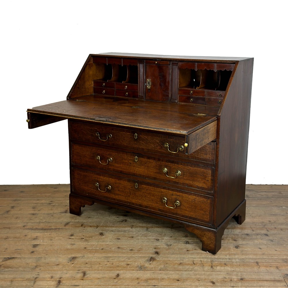 An antique Georgian oak writing bureau featuring a sloping fall-front lid above four drawers with brass swan-neck handles. View III