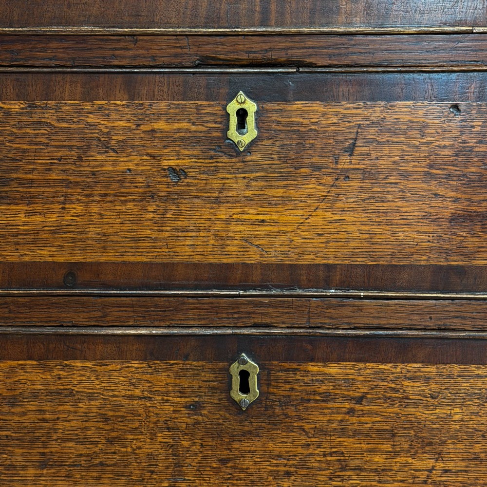 An antique Georgian oak writing bureau featuring a sloping fall-front lid above four drawers with brass swan-neck handles. View IV