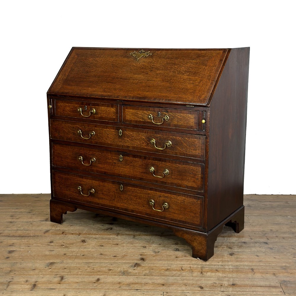 An antique Georgian oak writing bureau featuring a sloping fall-front lid above four drawers with brass swan-neck handles. View VII