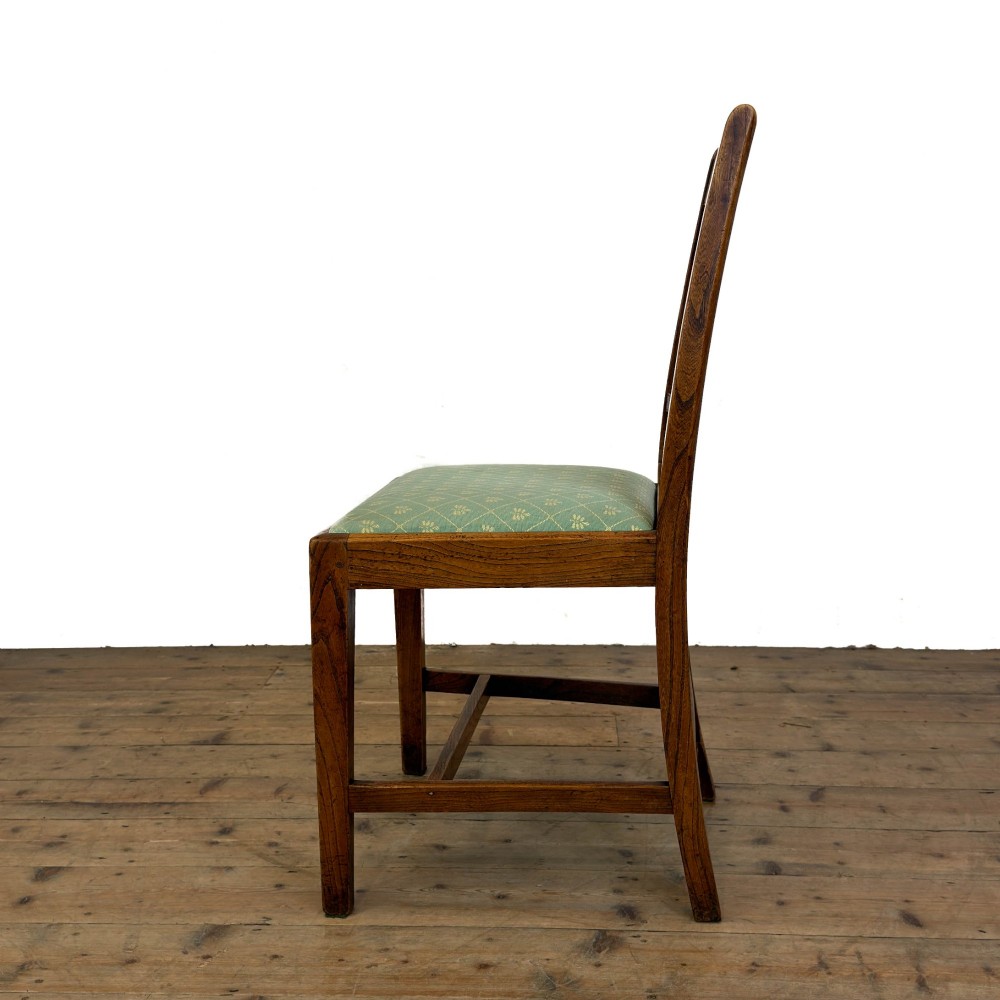 A set of six antique oak dining chairs, including two carvers, featuring geometric inlaid crest rails, decorative back splats, and light green patterned fabric seats. View V