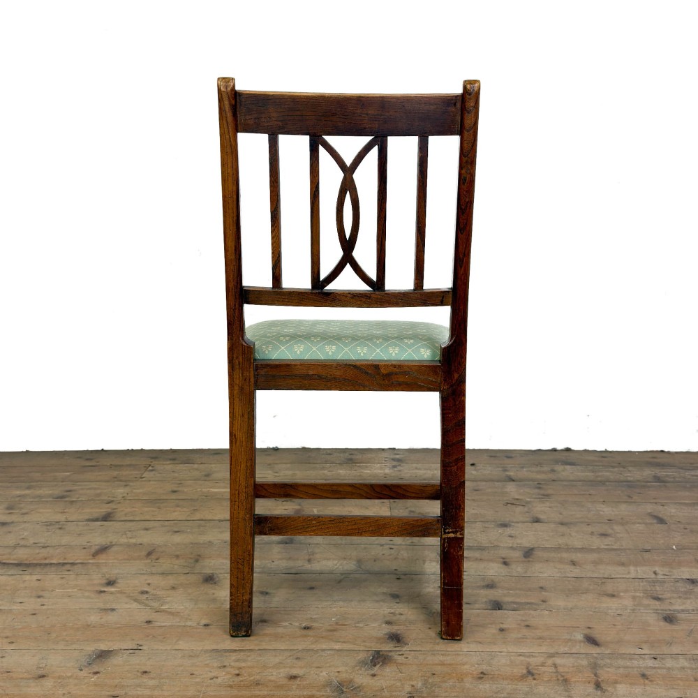 A set of six antique oak dining chairs, including two carvers, featuring geometric inlaid crest rails, decorative back splats, and light green patterned fabric seats. View VII