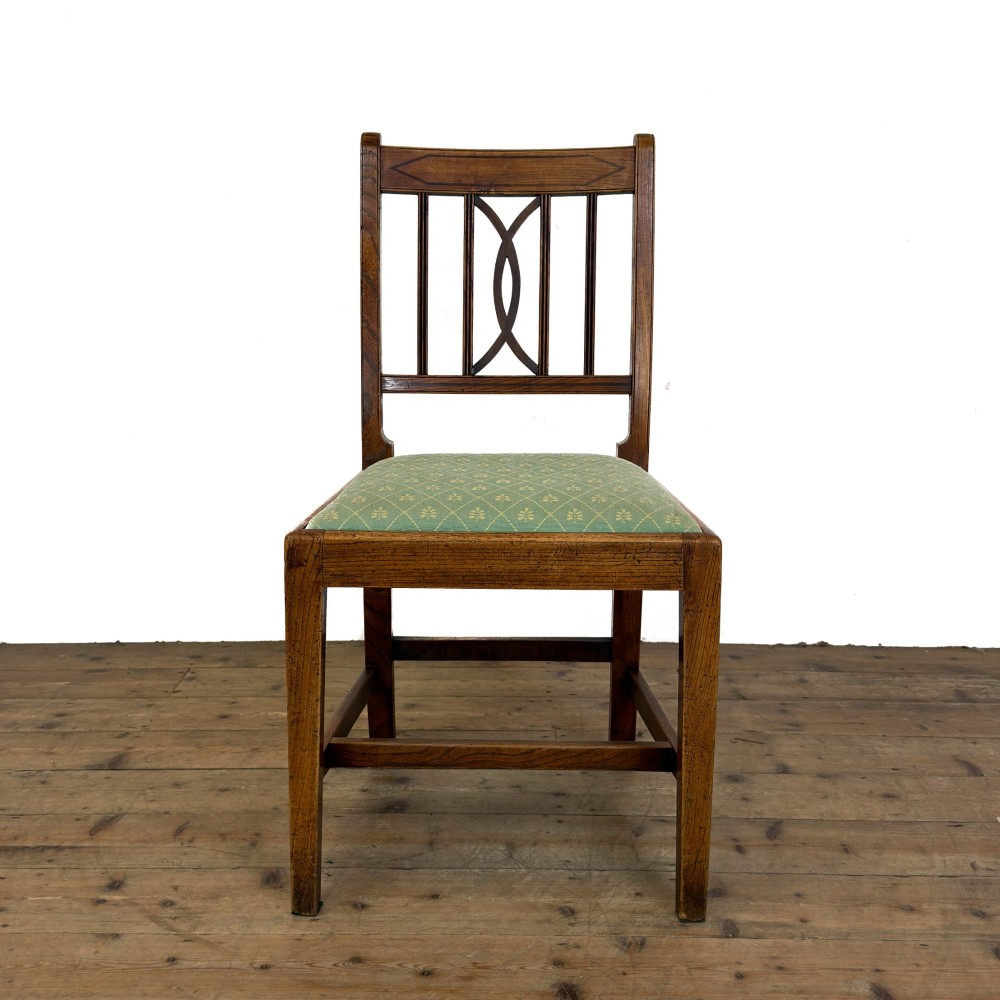 A set of six antique oak dining chairs, including two carvers, featuring geometric inlaid crest rails, decorative back splats, and light green patterned fabric seats. View X