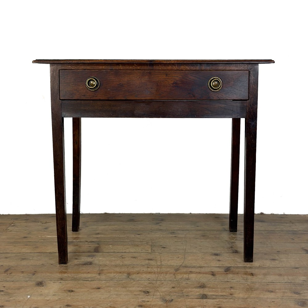 An antique dark oak lowboy side table featuring a single full-width drawer with circular brass handles and straight square legs.