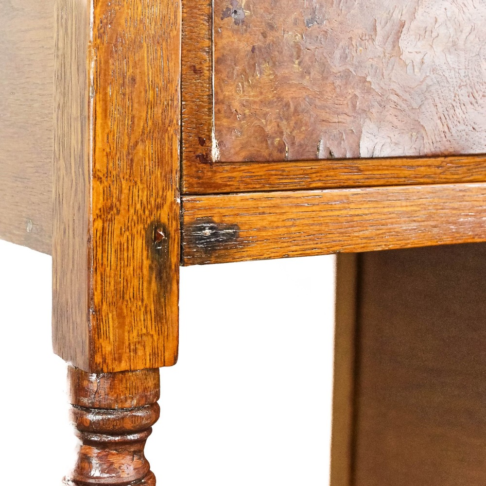 An antique Edwardian warm brown oak writing desk featuring five drawers with brass swing handles, turned legs, and brass castors. View IV