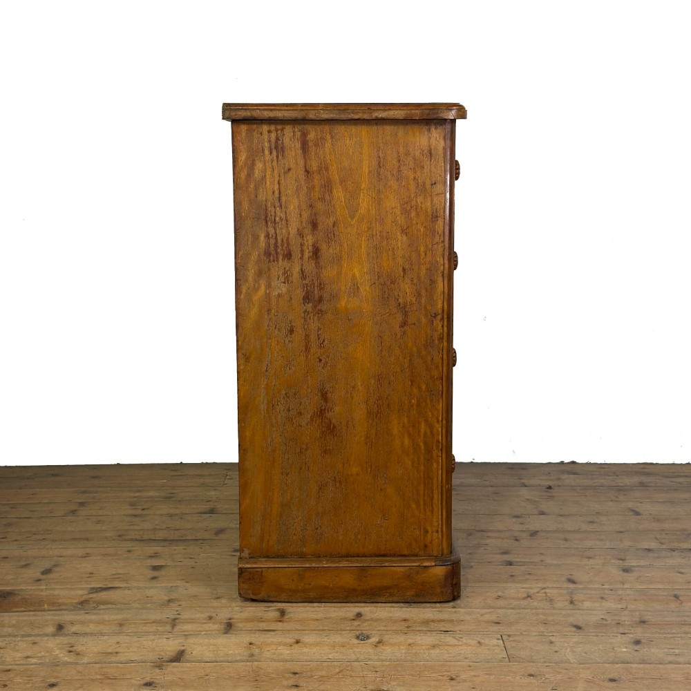 A Victorian mahogany chest of drawers featuring two short over three long drawers with carved fluted knobs and a plinth base. View VI