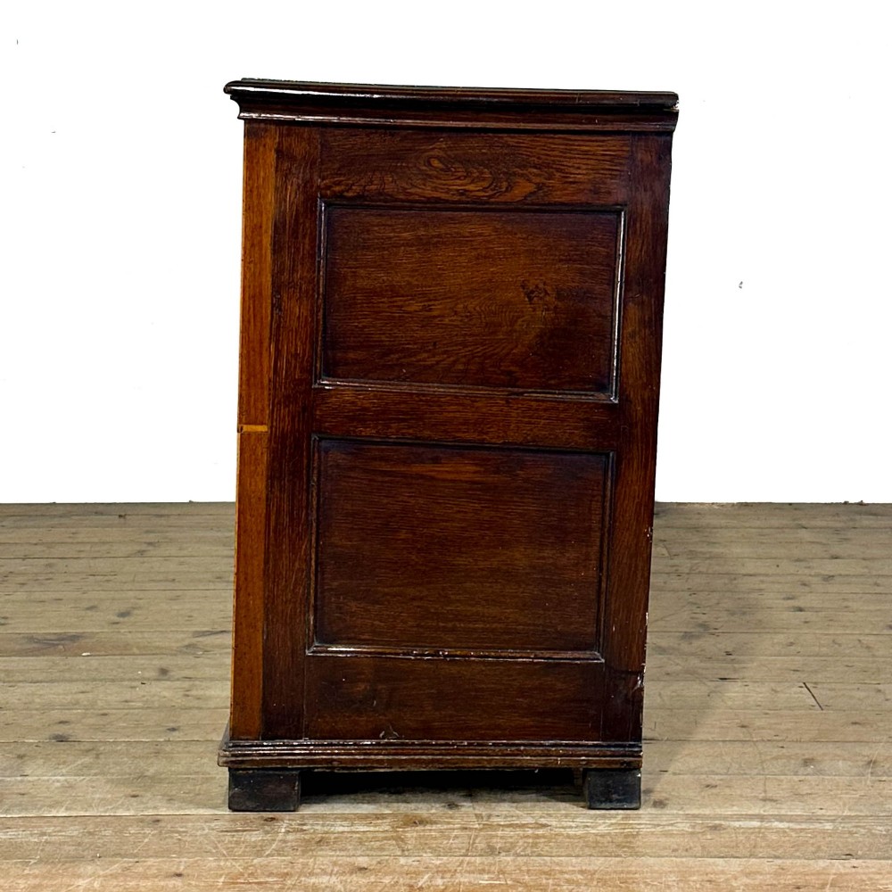 An antique Georgian oak dresser base featuring brass oval drop handles, panelled cupboard doors, central drawers, and geometric diamond inlay. View IV
