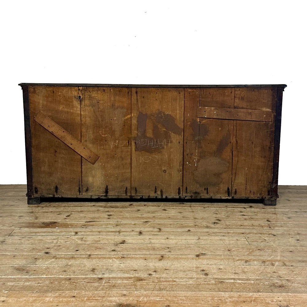 An antique Georgian oak dresser base featuring brass oval drop handles, panelled cupboard doors, central drawers, and geometric diamond inlay. View V