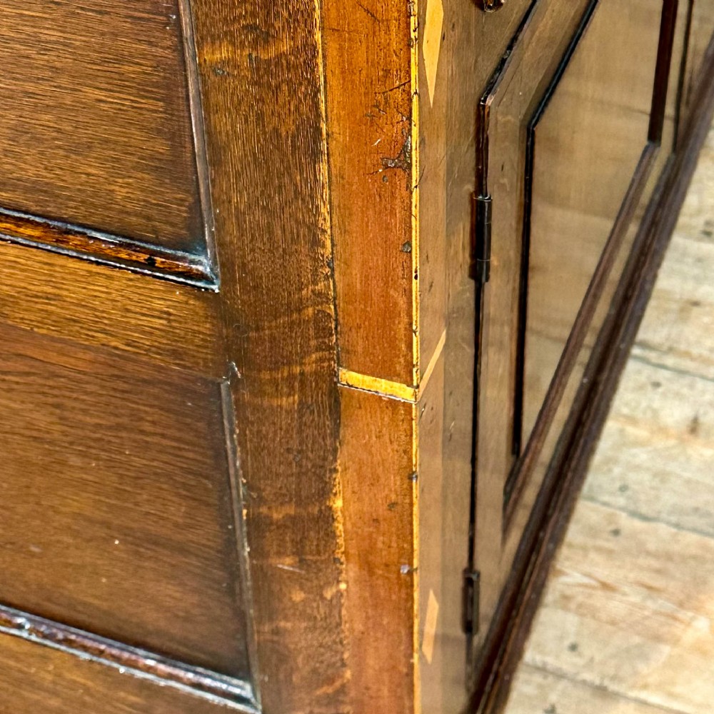 An antique Georgian oak dresser base featuring brass oval drop handles, panelled cupboard doors, central drawers, and geometric diamond inlay. View VII