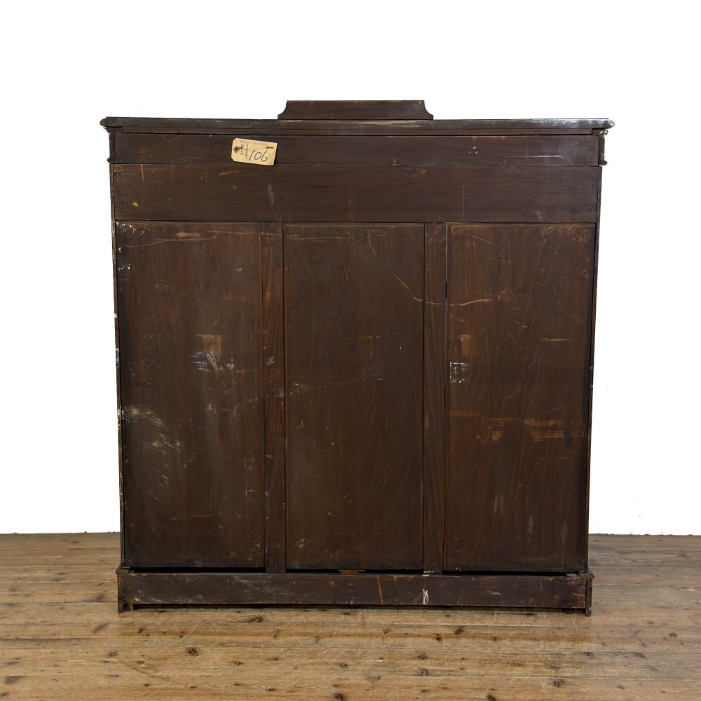 An Edwardian dark mahogany display cabinet featuring two glazed doors, satinwood scroll marquetry along the top frieze, and internal wooden shelves. View III