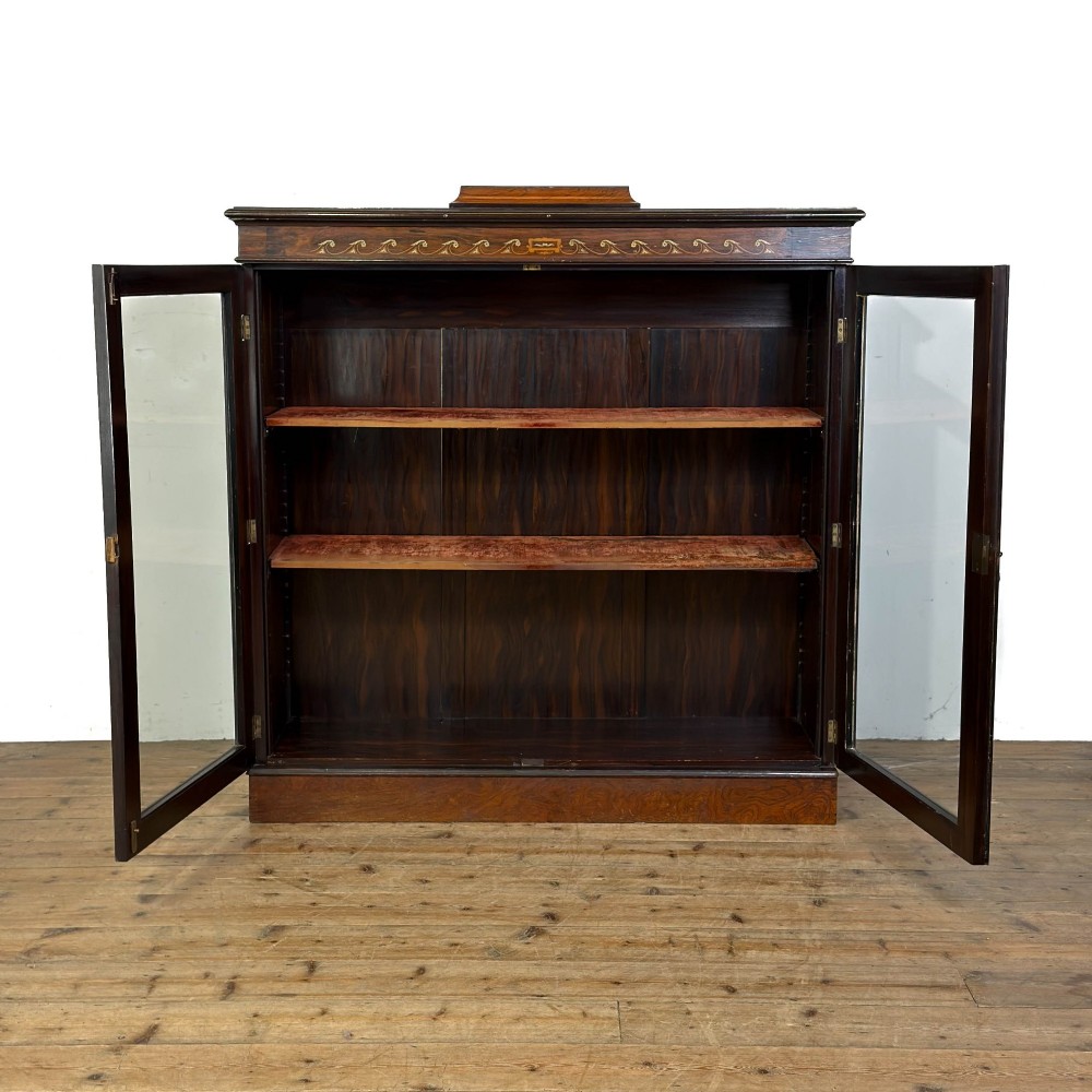An Edwardian dark mahogany display cabinet featuring two glazed doors, satinwood scroll marquetry along the top frieze, and internal wooden shelves. View VII