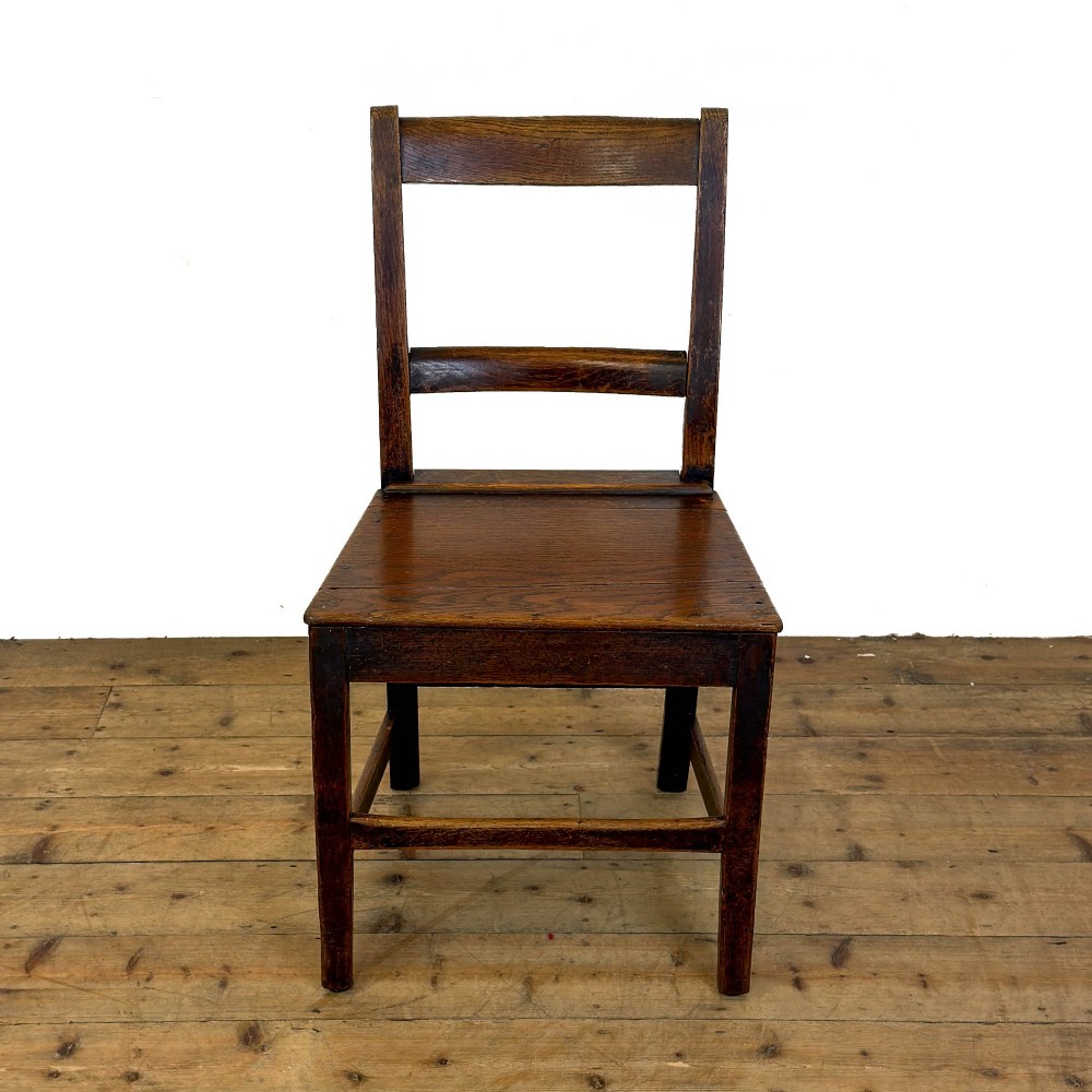 A harlequin set of four dark brown oak country dining chairs featuring horizontal ladder backs and solid wood seats on square legs. View V