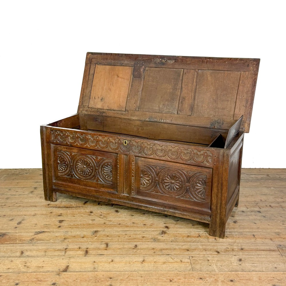 An 18th-century dark carved oak coffer featuring rosette panel relief carvings, a lunette frieze, and a brass keyhole escutcheon. View III