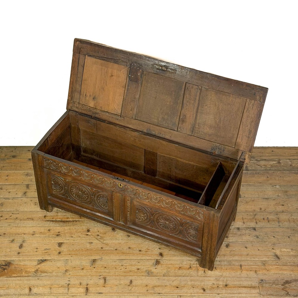An 18th-century dark carved oak coffer featuring rosette panel relief carvings, a lunette frieze, and a brass keyhole escutcheon. View IV