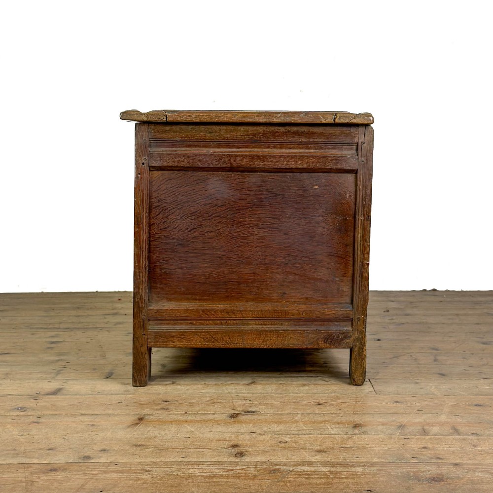 An 18th-century dark carved oak coffer featuring rosette panel relief carvings, a lunette frieze, and a brass keyhole escutcheon. View VI