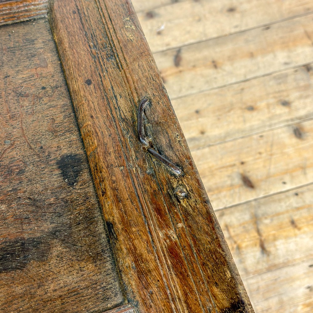 An 18th-century dark carved oak coffer featuring rosette panel relief carvings, a lunette frieze, and a brass keyhole escutcheon. View VII
