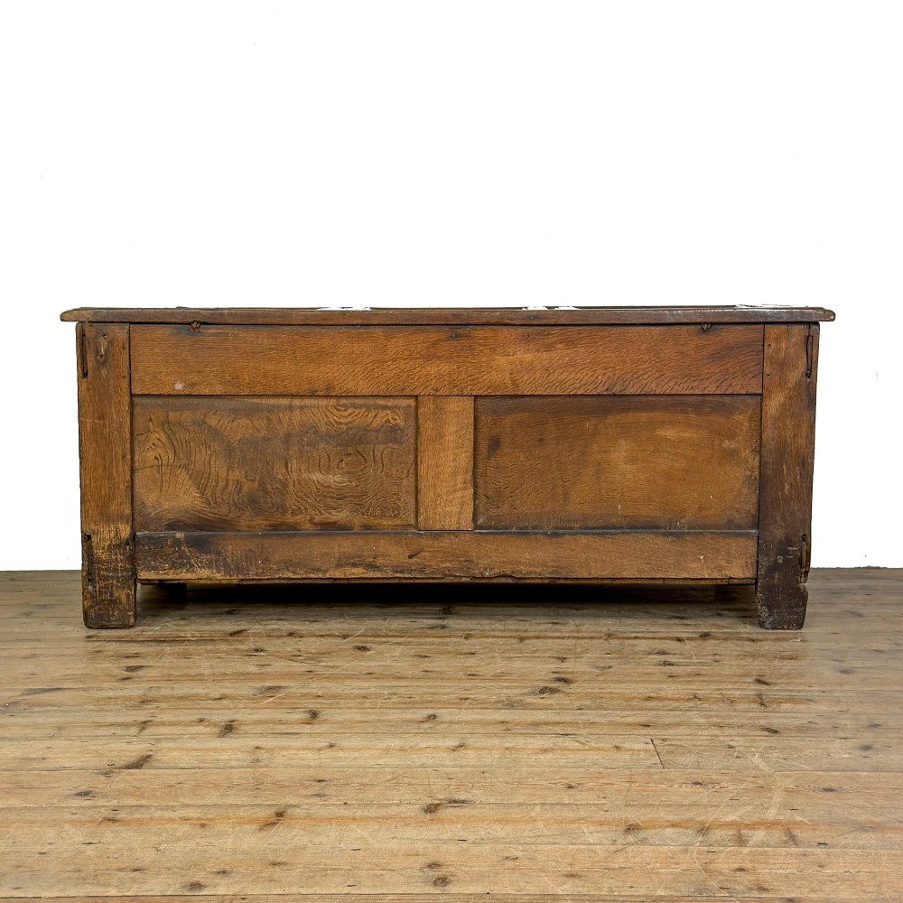 An 18th-century dark carved oak coffer featuring rosette panel relief carvings, a lunette frieze, and a brass keyhole escutcheon. View VIII
