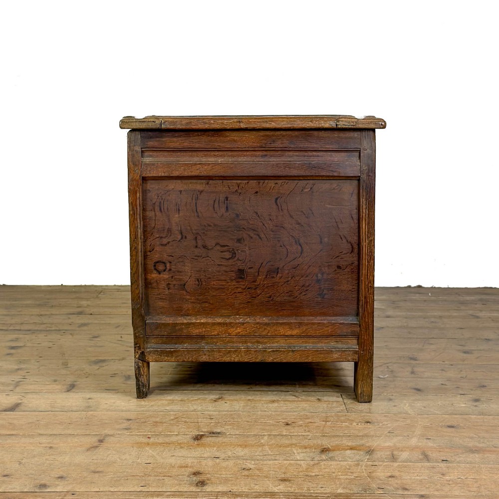 An 18th-century dark carved oak coffer featuring rosette panel relief carvings, a lunette frieze, and a brass keyhole escutcheon. View IX