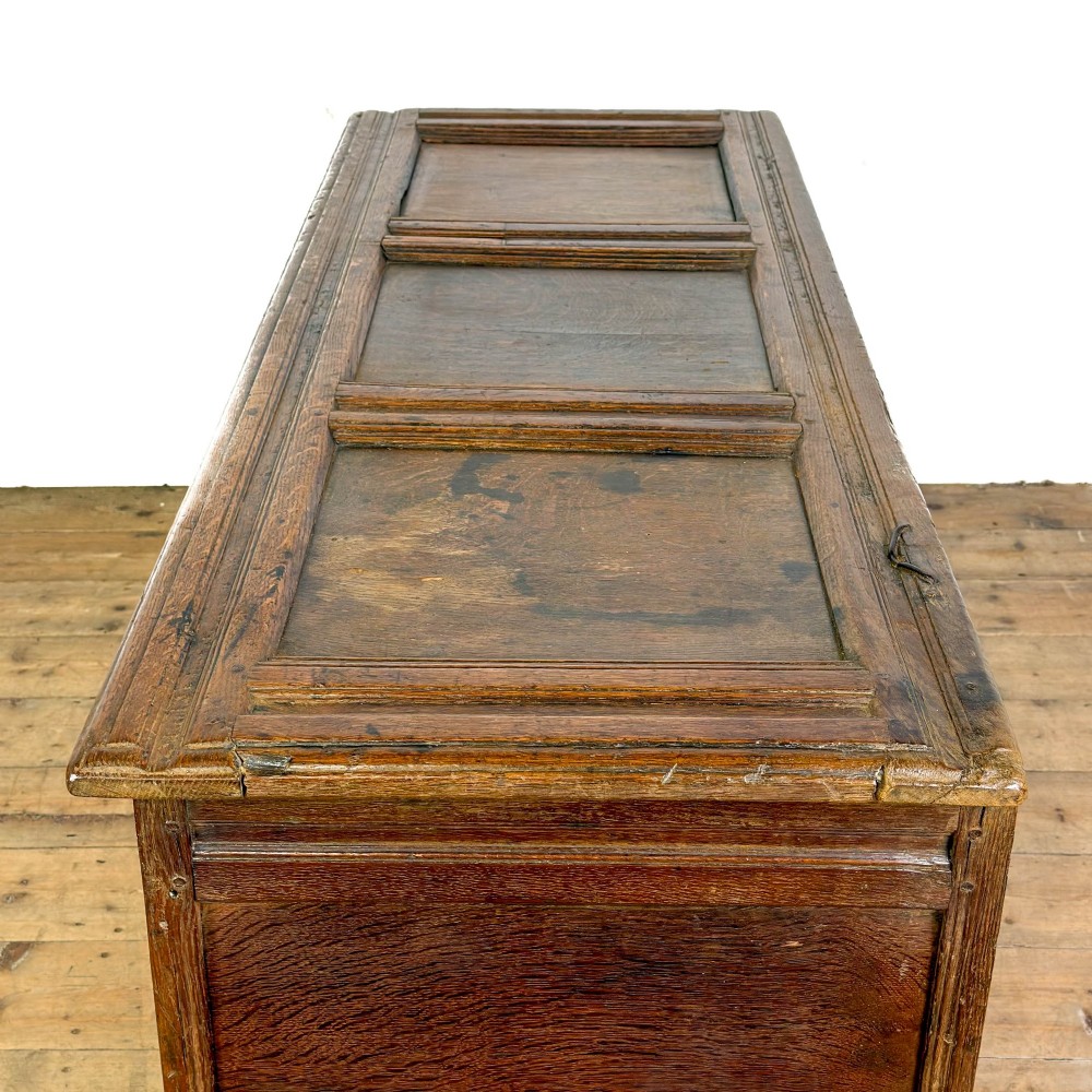 An 18th-century dark carved oak coffer featuring rosette panel relief carvings, a lunette frieze, and a brass keyhole escutcheon. View X