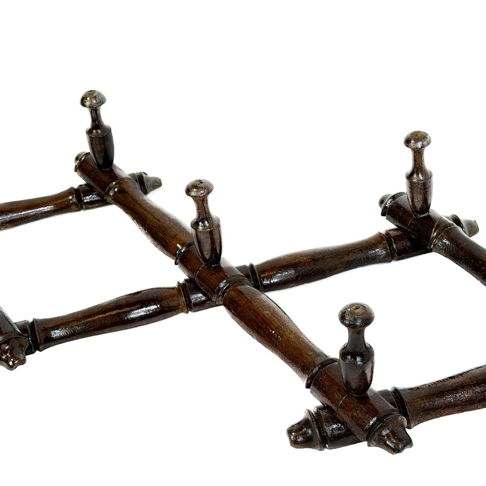 A dark brown wooden extending accordion coat rack with turned pegs arranged in a diamond lattice frame. View VI