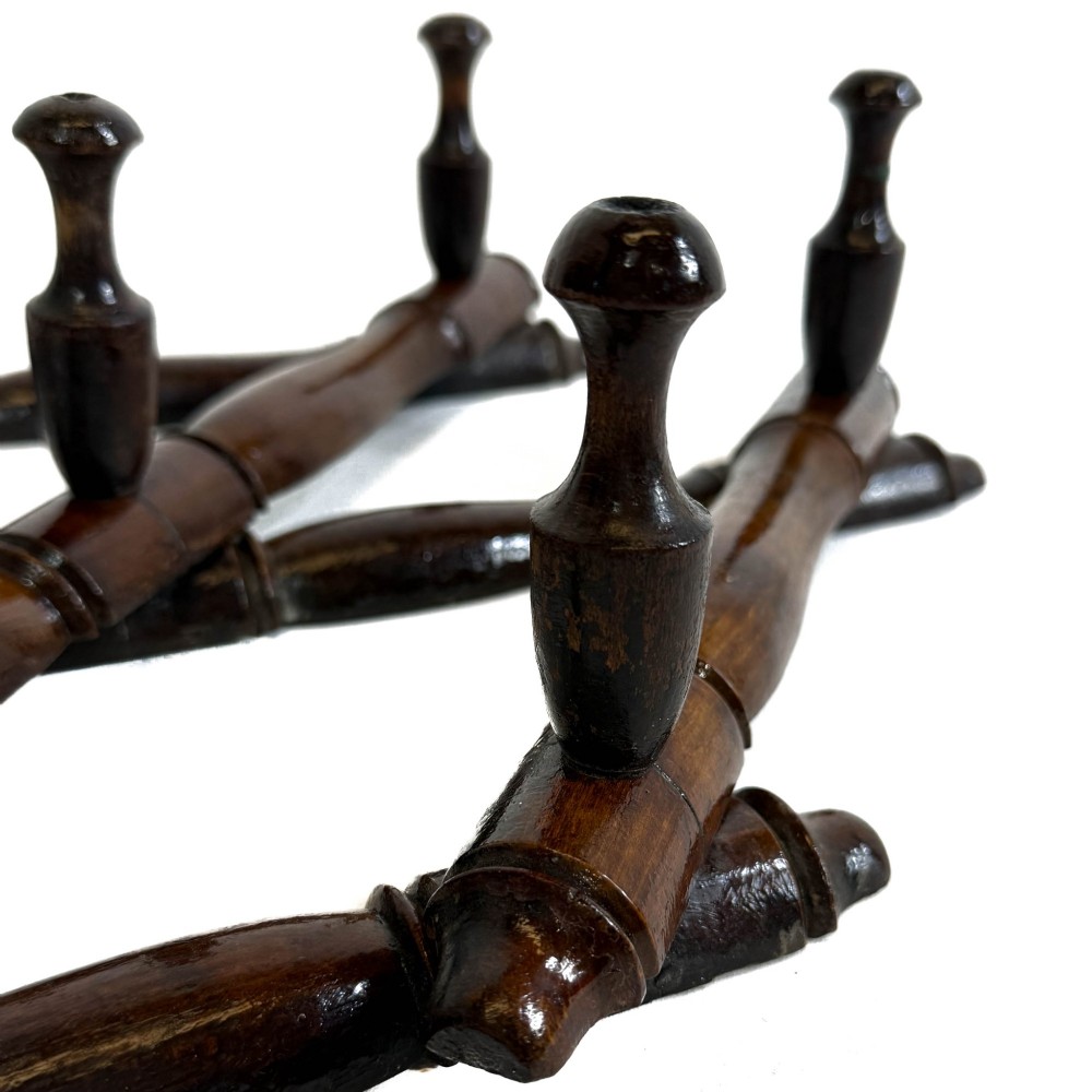 A dark brown wooden extending accordion coat rack with turned pegs arranged in a diamond lattice frame. View IX