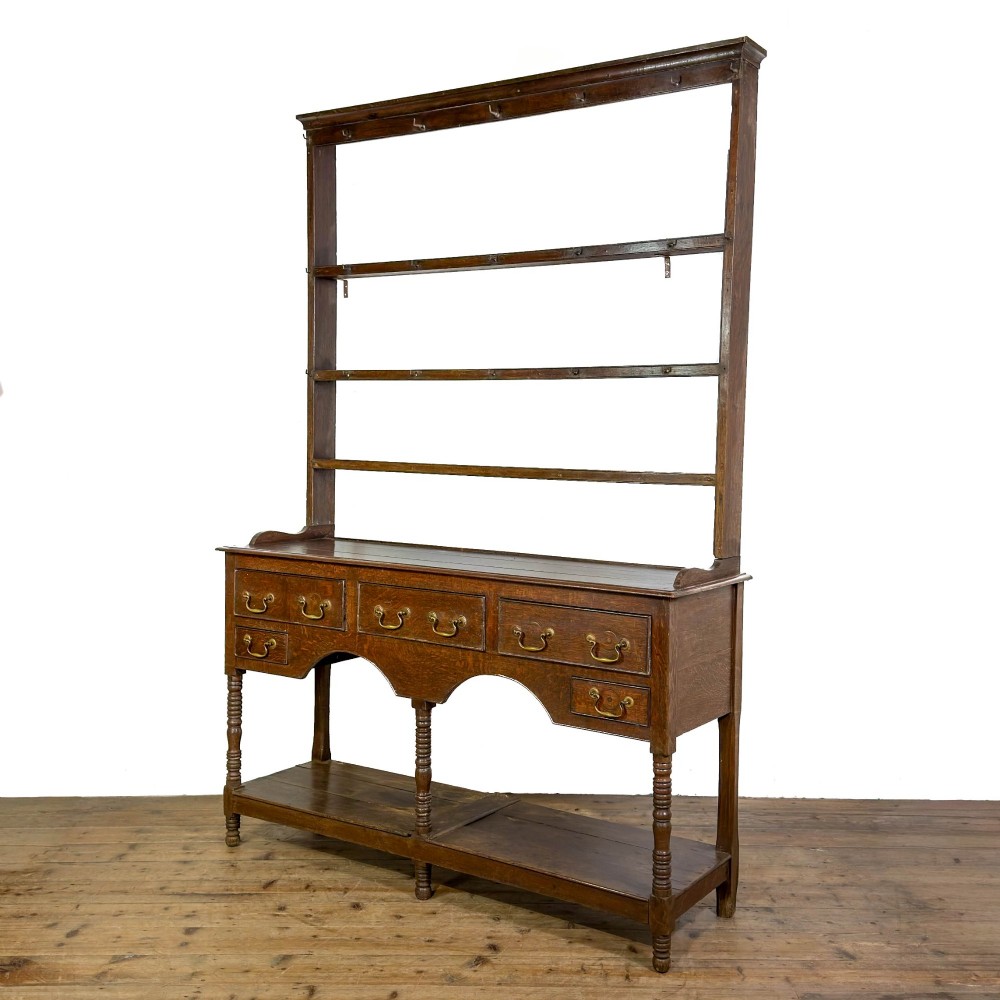A 19th-century dark oak Welsh potboard dresser featuring an open three-shelf plate rack resting on a five-drawer base with turned legs. View II