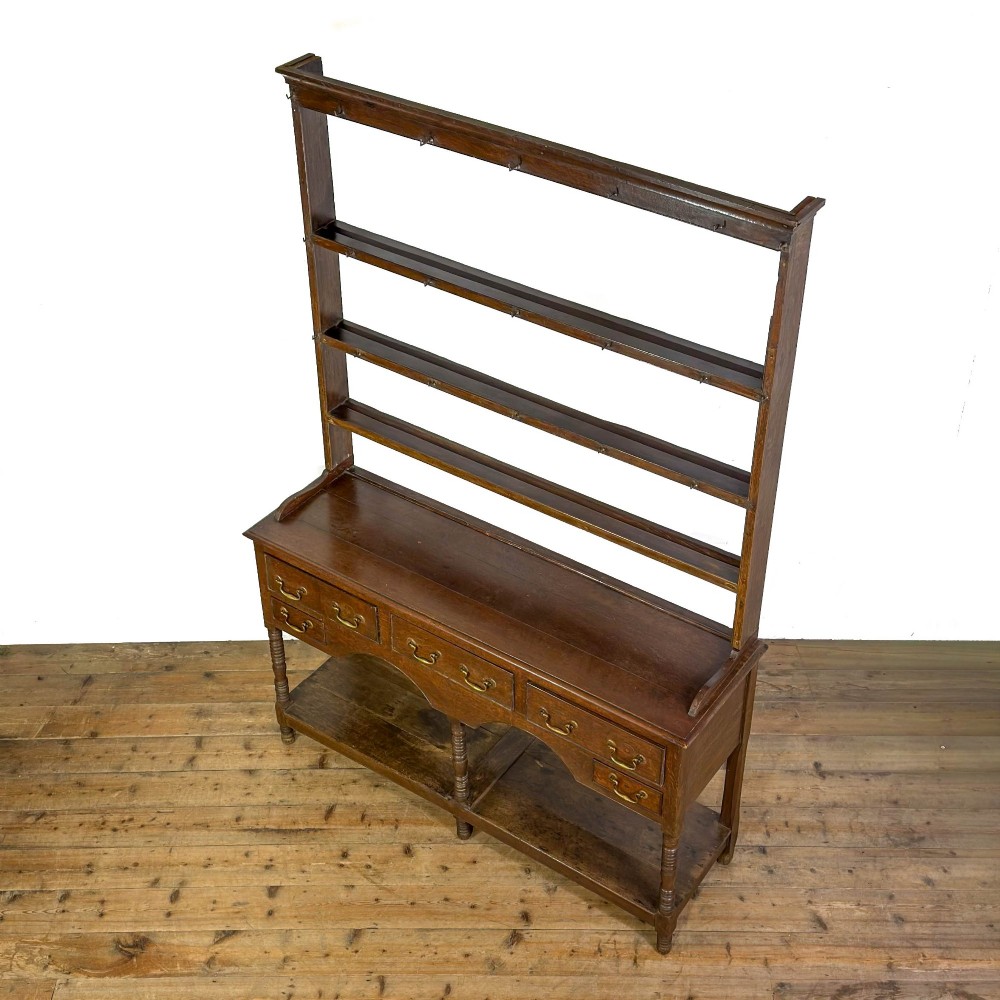 A 19th-century dark oak Welsh potboard dresser featuring an open three-shelf plate rack resting on a five-drawer base with turned legs. View III