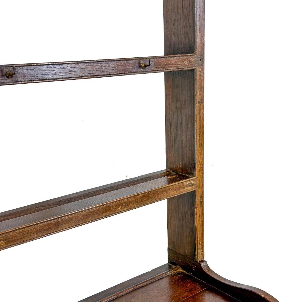 A 19th-century dark oak Welsh potboard dresser featuring an open three-shelf plate rack resting on a five-drawer base with turned legs. View IV