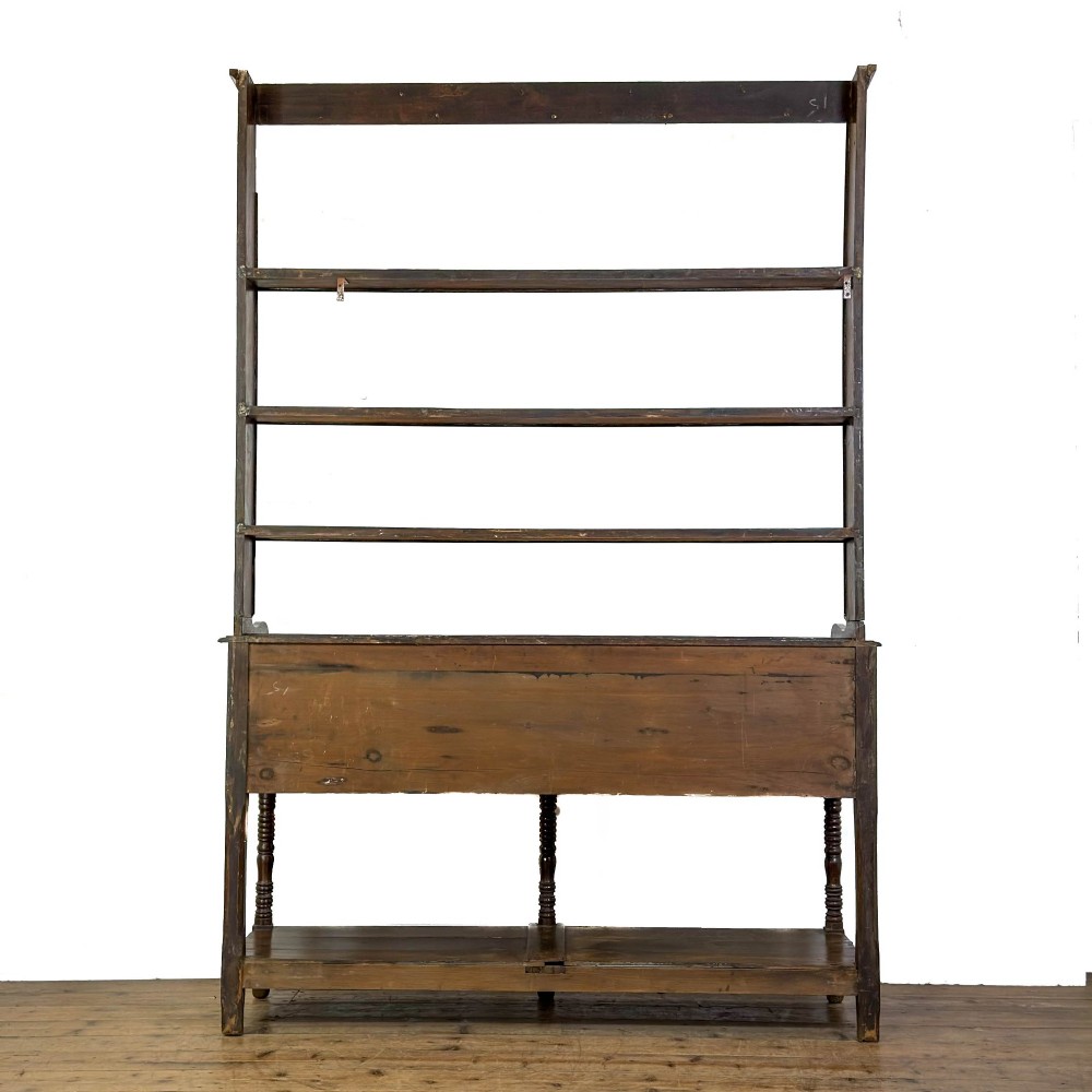 A 19th-century dark oak Welsh potboard dresser featuring an open three-shelf plate rack resting on a five-drawer base with turned legs. View V