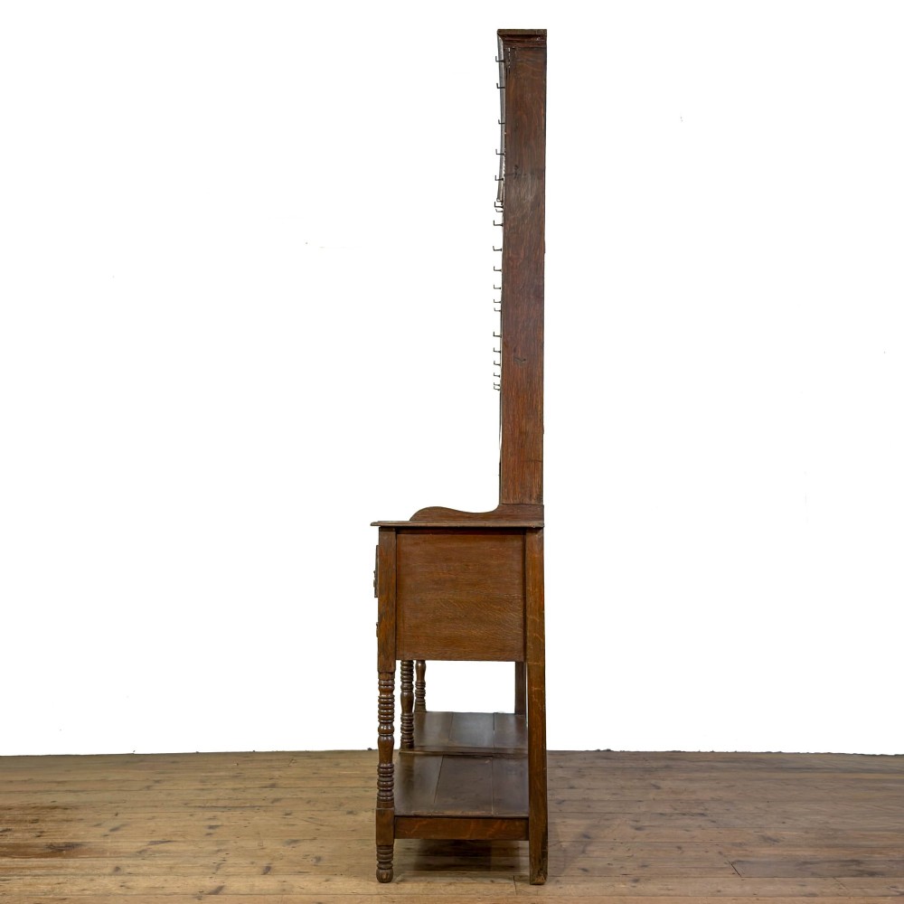 A 19th-century dark oak Welsh potboard dresser featuring an open three-shelf plate rack resting on a five-drawer base with turned legs. View VI