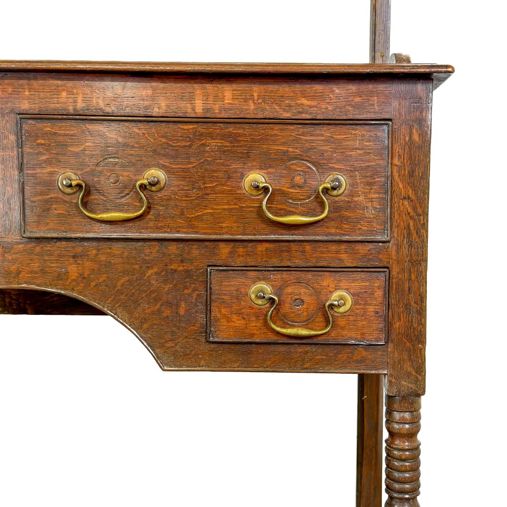 A 19th-century dark oak Welsh potboard dresser featuring an open three-shelf plate rack resting on a five-drawer base with turned legs. View VII