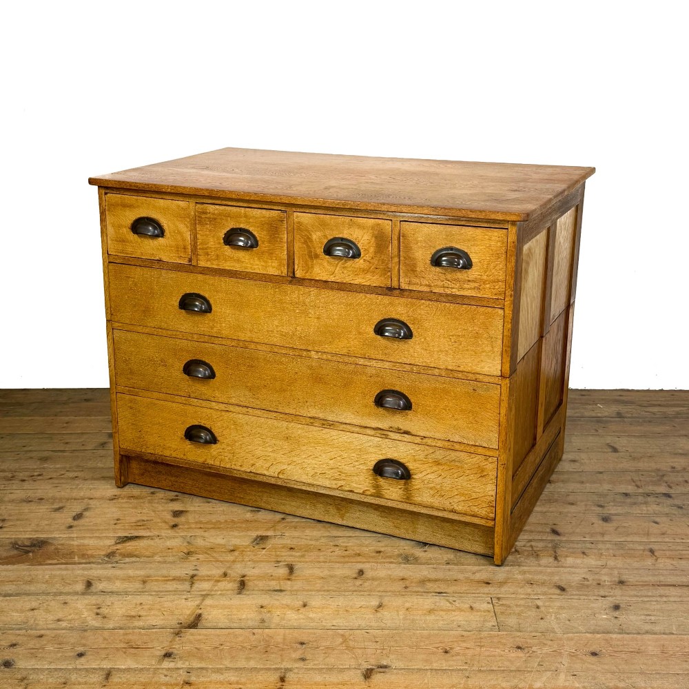 A vintage pale oak chest of drawers featuring four small top drawers above three wide drawers, fitted with dark metal cup handles. View II
