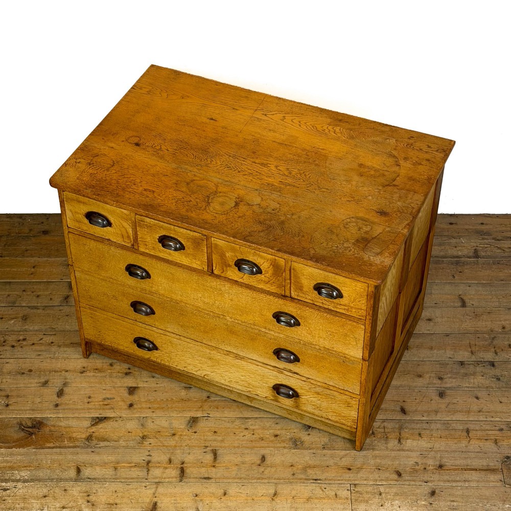 A vintage pale oak chest of drawers featuring four small top drawers above three wide drawers, fitted with dark metal cup handles. View III