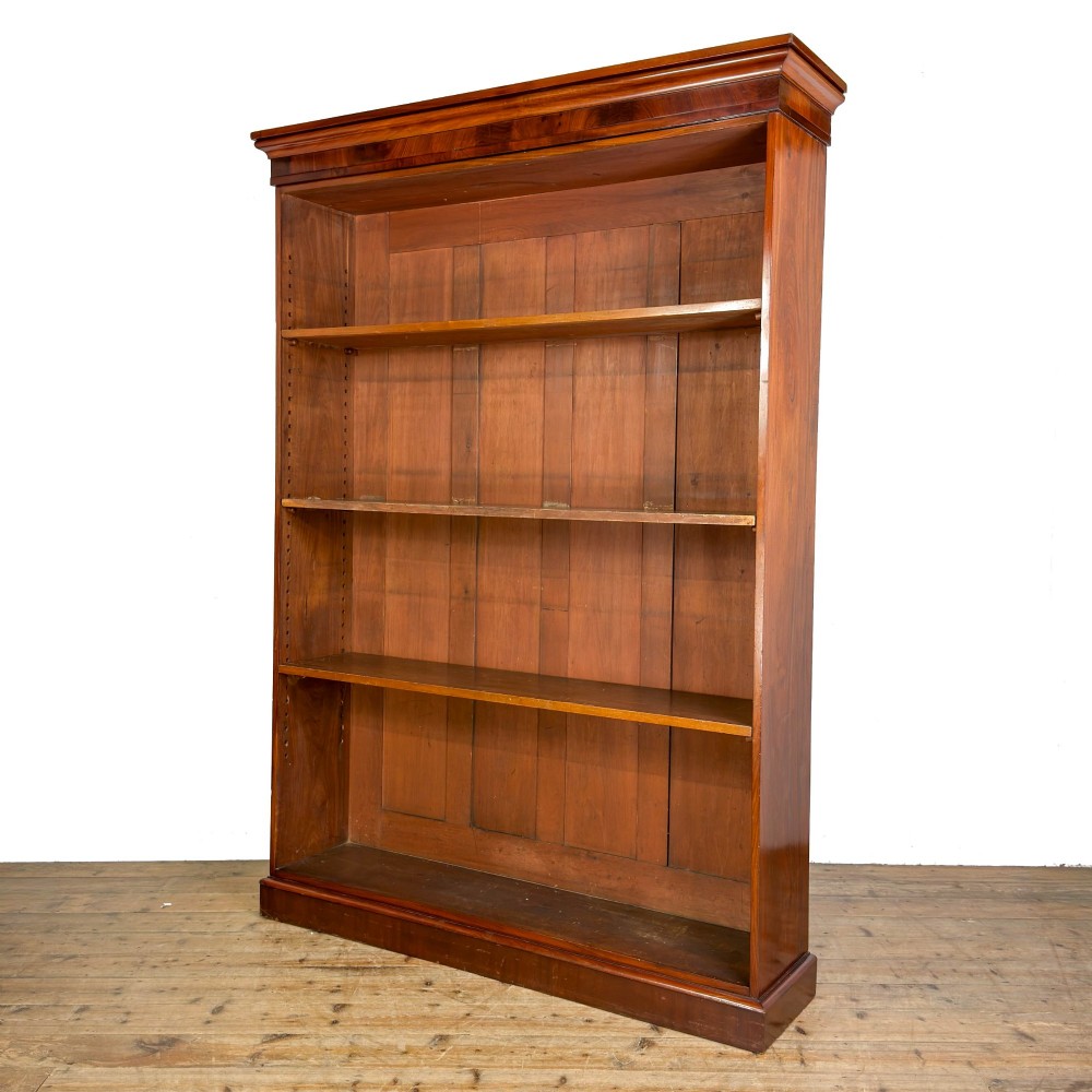 A large antique open mahogany bookcase with a moulded top cornice, multiple storage shelves, and vertical panelled timber backing. View II