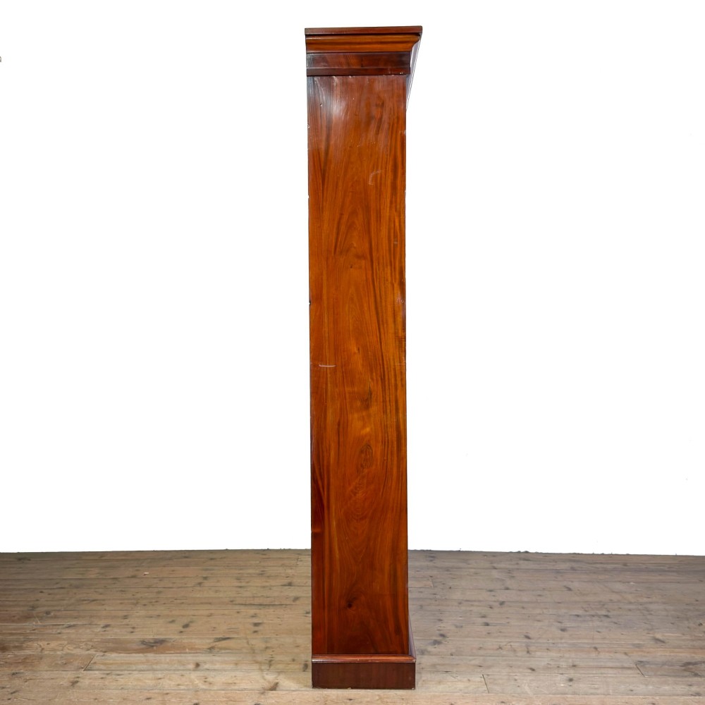A large antique open mahogany bookcase with a moulded top cornice, multiple storage shelves, and vertical panelled timber backing. View III