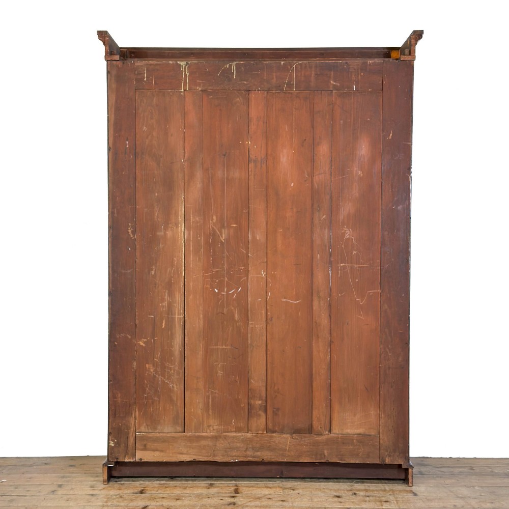 A large antique open mahogany bookcase with a moulded top cornice, multiple storage shelves, and vertical panelled timber backing. View V