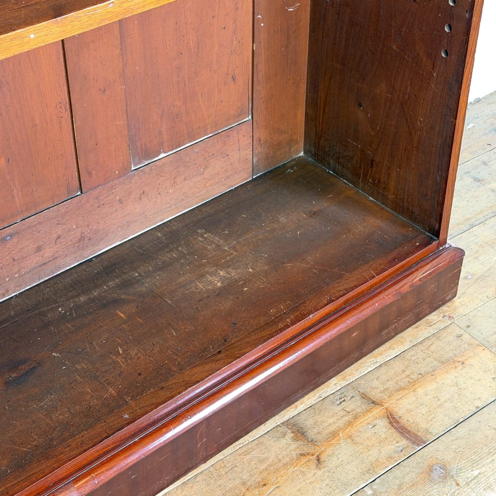 A large antique open mahogany bookcase with a moulded top cornice, multiple storage shelves, and vertical panelled timber backing. View VII