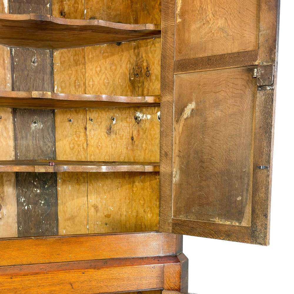 A two-tier freestanding Georgian oak corner cabinet with panelled double doors, brass keyhole escutcheons, and a moulded cornice. View VIII