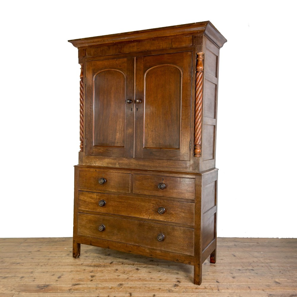 A 19th-century oak linen press featuring a two-door upper cupboard flanked by barley twist columns above a chest of drawers. View IV