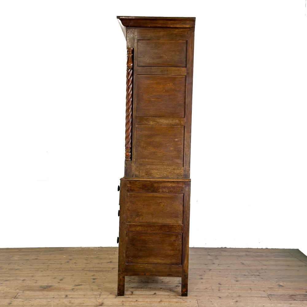 A 19th-century oak linen press featuring a two-door upper cupboard flanked by barley twist columns above a chest of drawers. View VII