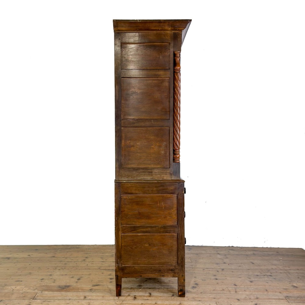 A 19th-century oak linen press featuring a two-door upper cupboard flanked by barley twist columns above a chest of drawers. View IX