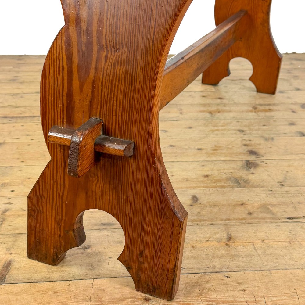 An antique pine bench featuring a long plank top, shaped trestle end supports, and a lower wooden stretcher rail. View IV