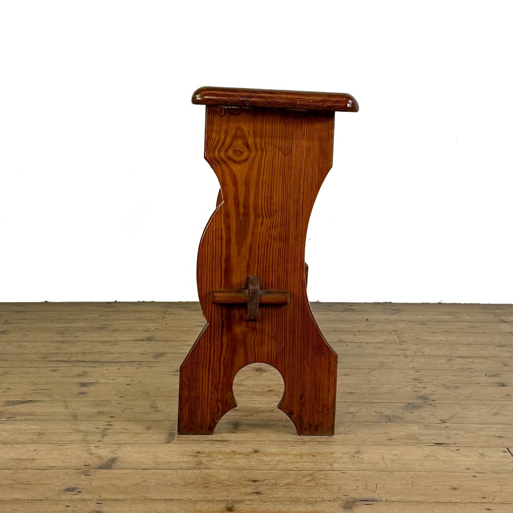 An antique pine bench featuring a long plank top, shaped trestle end supports, and a lower wooden stretcher rail. View V