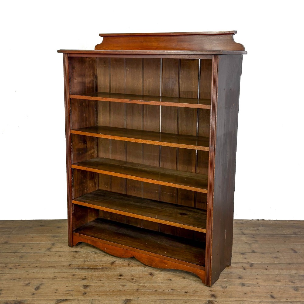 A tall 19th-century open wooden bookcase featuring five fixed shelves, fluted side stiles, a stepped pediment, and a shaped apron base. View II