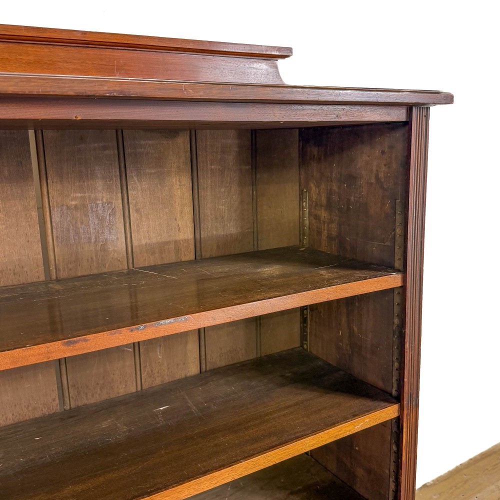 A tall 19th-century open wooden bookcase featuring five fixed shelves, fluted side stiles, a stepped pediment, and a shaped apron base. View IX