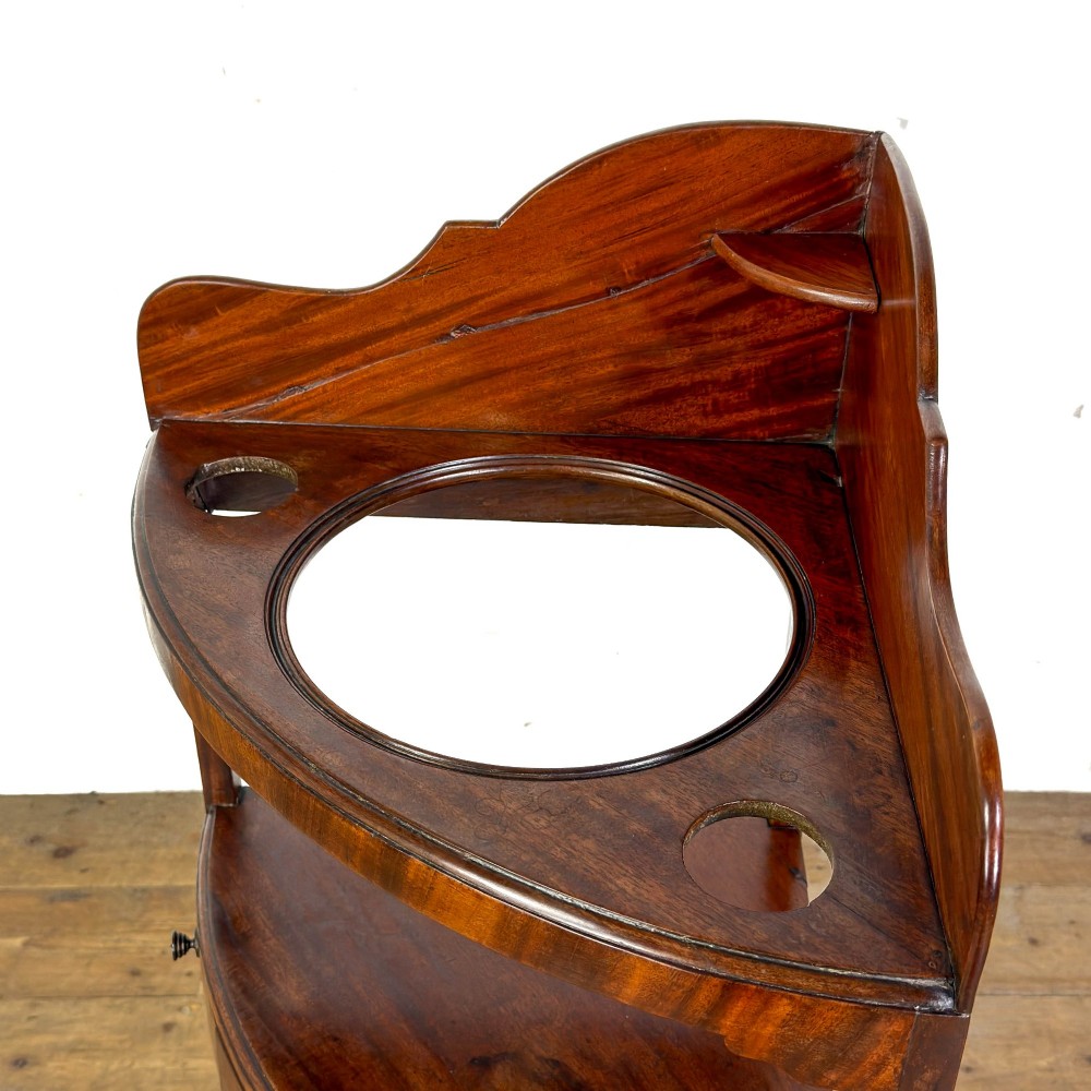 A Georgian mahogany corner washstand featuring a shaped splashback, middle drawer section with brass knobs, and curved splayed legs. View IV