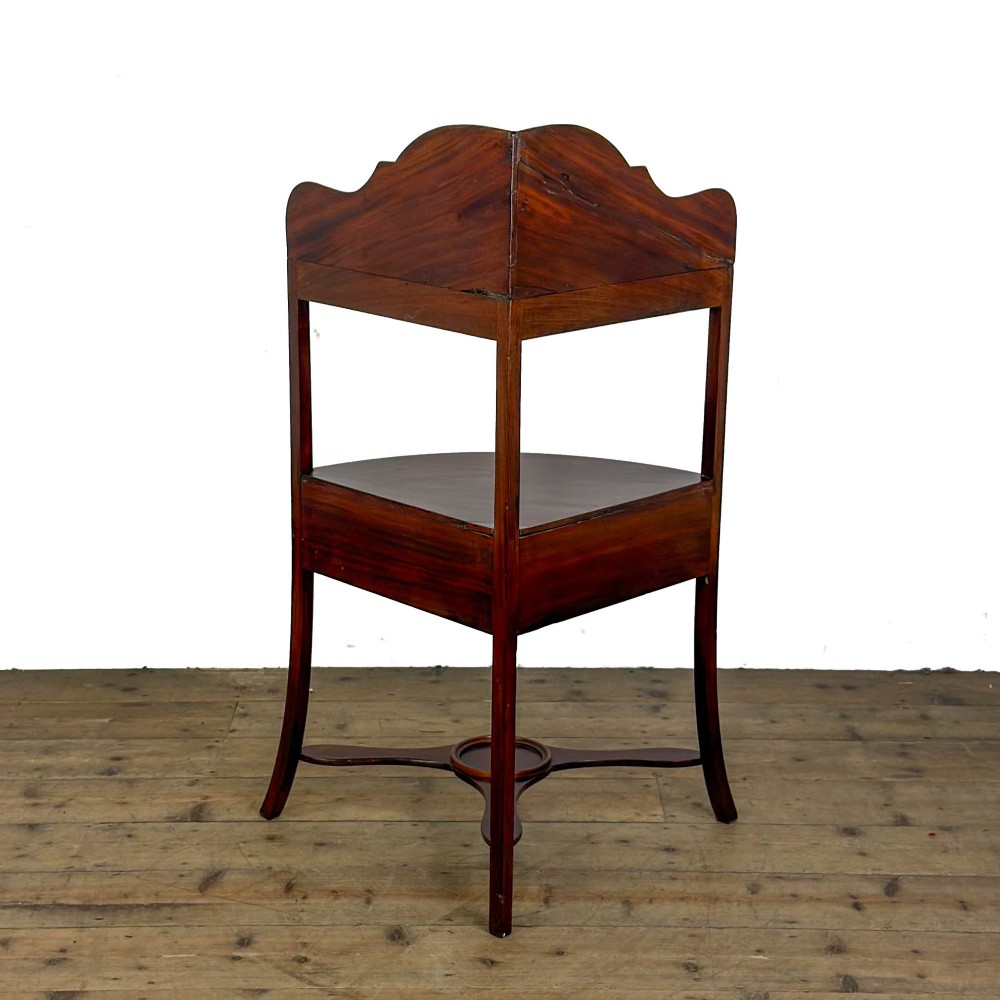 A Georgian mahogany corner washstand featuring a shaped splashback, middle drawer section with brass knobs, and curved splayed legs. View V