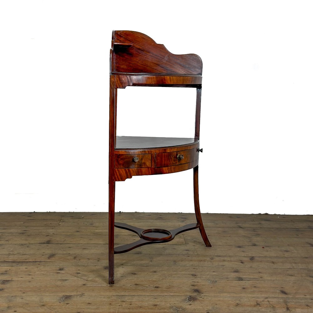 A Georgian mahogany corner washstand featuring a shaped splashback, middle drawer section with brass knobs, and curved splayed legs. View VII
