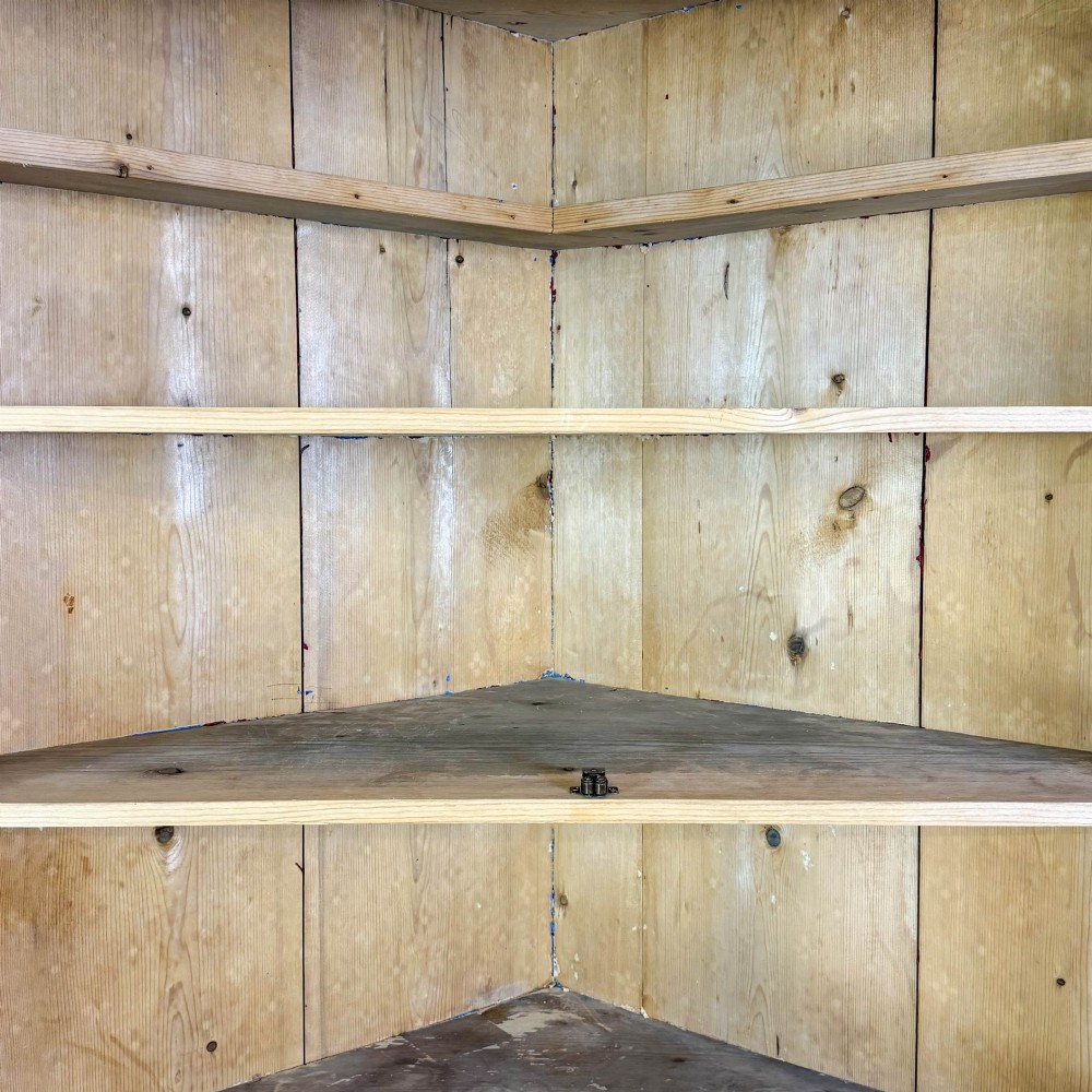 An antique stripped pine corner cabinet featuring arched glazed doors on the upper section, three drawers, and twin panelled cupboard doors below. View IX