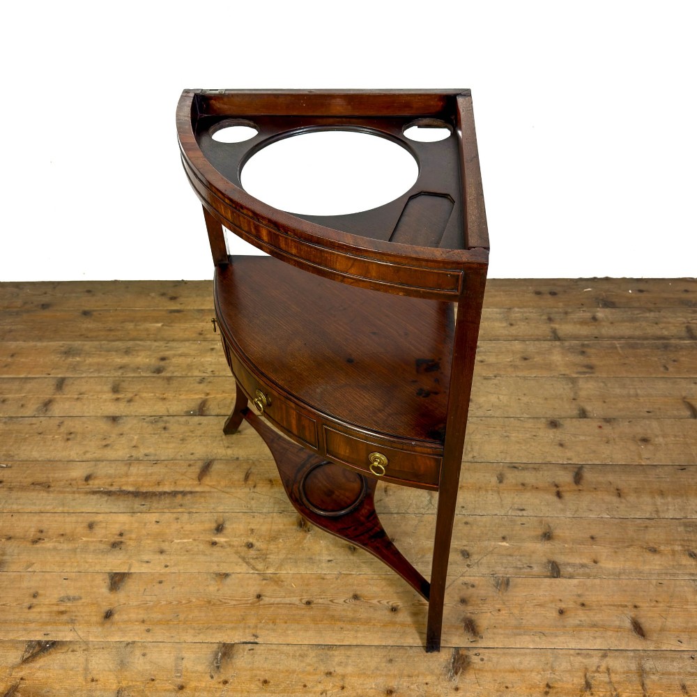 A Georgian dark mahogany triangular corner washstand featuring a smooth top shelf, a middle tier with three drawer fronts and brass ring handles, and slender legs connected by a lower stretcher. View III