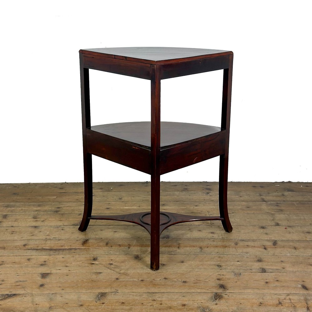 A Georgian dark mahogany triangular corner washstand featuring a smooth top shelf, a middle tier with three drawer fronts and brass ring handles, and slender legs connected by a lower stretcher. View V